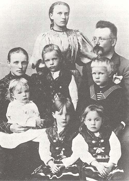 Familjen: rad 1) Elsa, Gertrud, rad 2) mamma med Ragnar, Gerda, Rolf, pappa, rad 3) Nanna. 